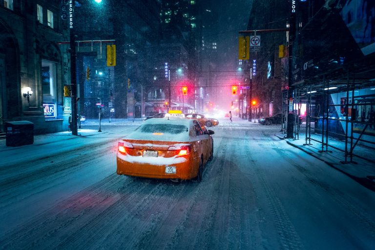 a car driving down a snow covered street at night